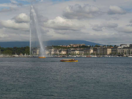 yellow ferry boats sail past the fountain on lake genevaの写真素材