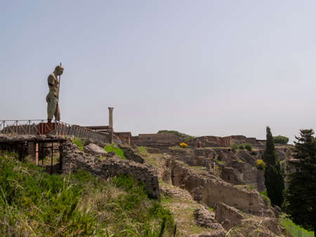NAPLES, ITALY- JUNE, 13, 2019: ruined buildings and a modern art bronze statue of a soldier with a spear at pompeii ruinsのeditorial素材