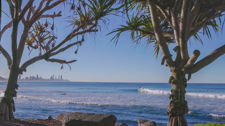 a wide angle shot of a surfer riding a wave on a beautiful sunny winter's afternoon at burleigh heads in queensland, australiaの写真素材