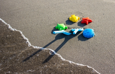 Toys on beach with wave and foamの写真素材