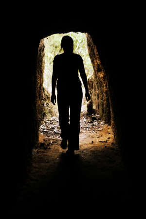 Looking towards the entrance of a cave with a woman walking forwardsの写真素材