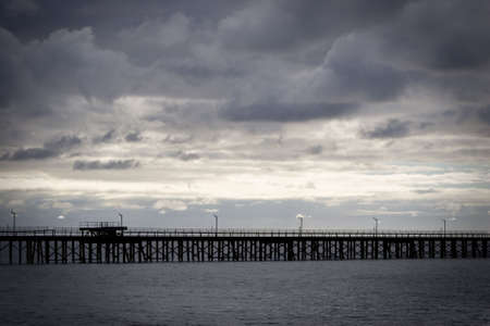 Long jetty/pier with looming clouds overheadの写真素材