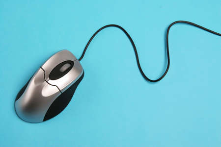 Computer mouse on a blue background with cord showing