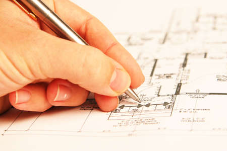 hand holding a pen, drawing building plans
