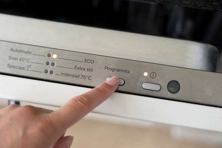 Woman hand choosing eco program on dish washer