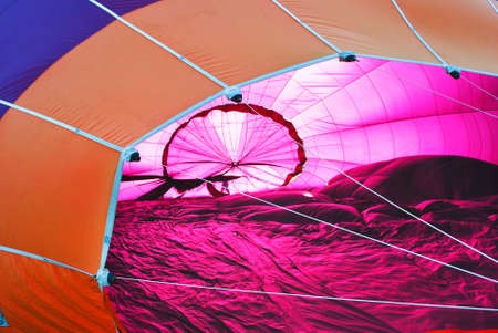 Hot air balloon laying on the ground, ready to get blown up, pink on the inside, purple and orange on the outsideの写真素材