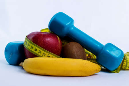 dumbbell and fruits apple, orange, banana, kiwi (white background)の写真素材