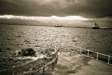 A dangerous pier with waves crashing against the stairsの写真素材