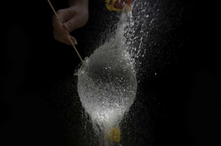A yellow balloon filled with water frozen as it pops の写真素材