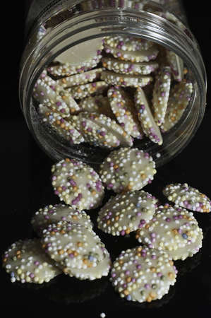 Multicoloured sprinkles on a white chocolate buttonの写真素材