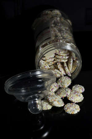 A display of multicoloured sprinkles on a white chocolate buttonの写真素材