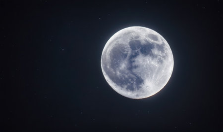A full moon hangs in the night sky, its craters and shadows visible against the dark backgroundの素材