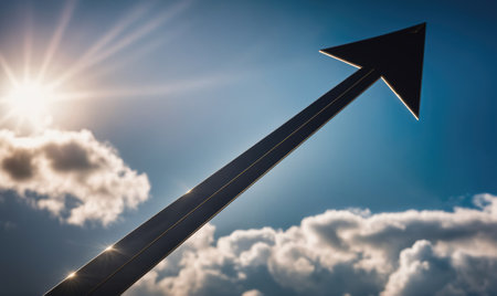 A large arrow points upward against a bright blue sky with fluffy cloudsの素材