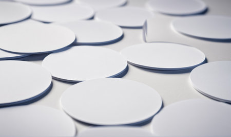 White, round coasters lay scattered on a white surfaceの素材
