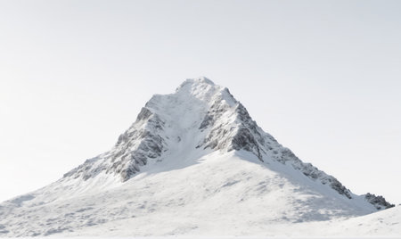 A snow-covered mountain peak stands tall against a clear, white skyの素材