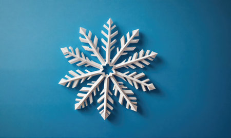 A white paper snowflake rests on a blue backgroundの素材