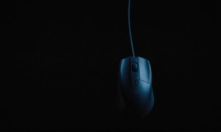 A dark blue computer mouse hangs against a black backgroundの素材