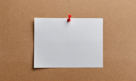 A blank white note is pinned to a brown corkboard with a red pushpinの素材