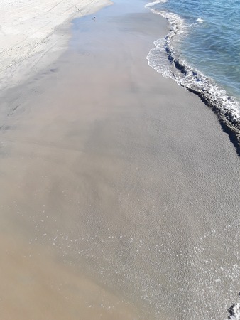 Soft wave of blue ocean on sandy beach. Background. Selective focus. Wave of the sea on the sand...