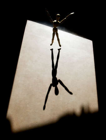 Artist's model with heavy backlight and arms outstretched throws a long shadow.の写真素材