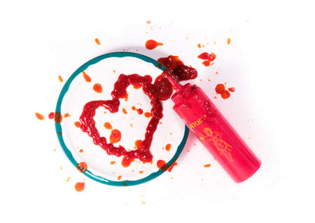 Red ktchup heart on a plate along with the squeeze bottle.