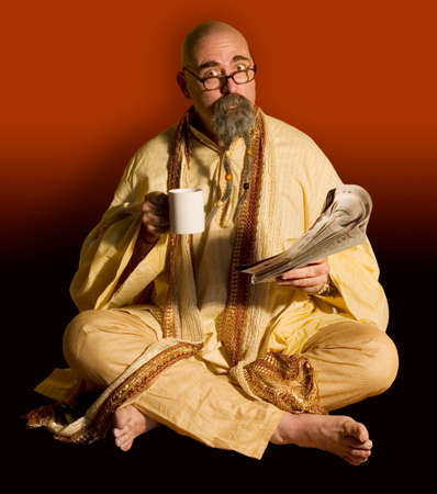 Funny guru sitting lotus style taking a coffee break while reading the newspaper..