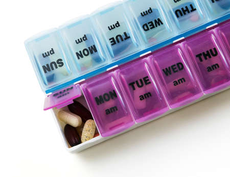 Supplement or medication dispenser open showing capsules and pills.