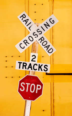 Railroad crossing stop sign against a yellow train car.の写真素材