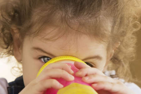Young girl drinking from a pink plastic sipping cupの写真素材