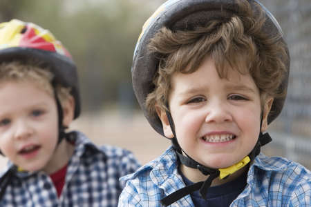 Two little boys in bicycle helmets - one boy looks concernedの写真素材