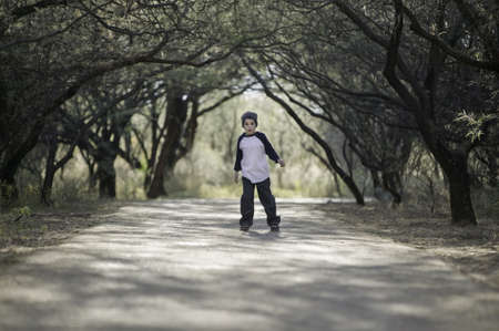 Young boy with a knit cap stopped on a tree-lined pathの写真素材