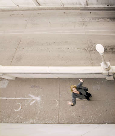 Wide shot from above of woman on a sidewalk with her hands in the airの写真素材