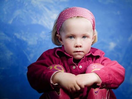 Little girl in studio in front of a blue wallの写真素材