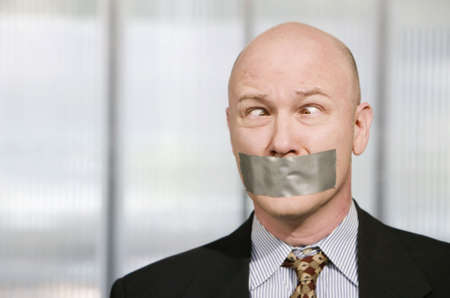 Cross-eyed businessman silenced with duct tape over his mouthの写真素材