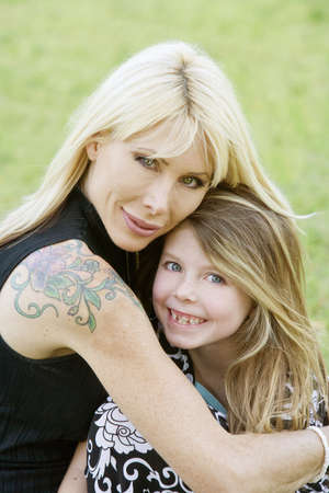 Pretty mom hugs her cute freckle-faced daughterの写真素材