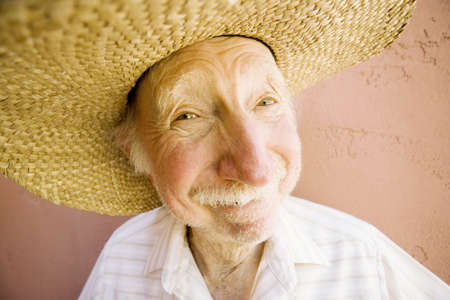 Senior Citizen Man with a Funny Expression Wearing a Straw Cowboy Hatの写真素材