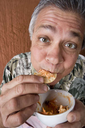 Close Up of a Man Eating Chip Dip from a Bowlの写真素材