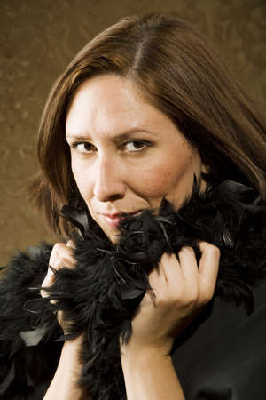 Pretty Hispanic Woman Wearing a Feather Boa in front of Gold Wallpaper