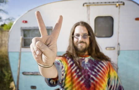 Friendly Hippie with Long Hair in Front of His Trailer making a peace Signの写真素材