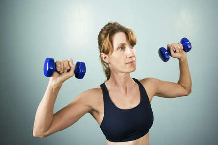 Pretty athletic woman working out with dumbbells