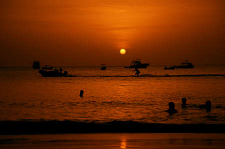 Swimmers and water skier in the Pacific Ocean at sunsetの写真素材