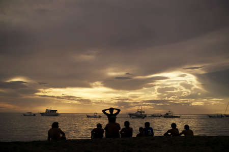 Costa Rica sunset with Boats and silhouettes of people on beachの写真素材