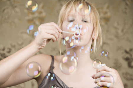 Pretty young girl with blue eyes blowing bubblesの写真素材