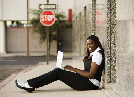 Pretty African American woman on sidealk with laptop computerの写真素材