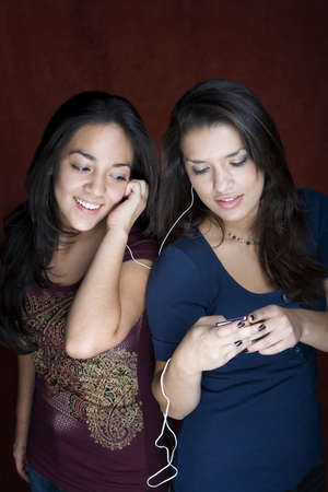 Two pretty Hispanic women sharing a headset listening to musicの写真素材