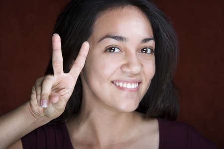 Pretty young Hispanic woman making peace signの写真素材