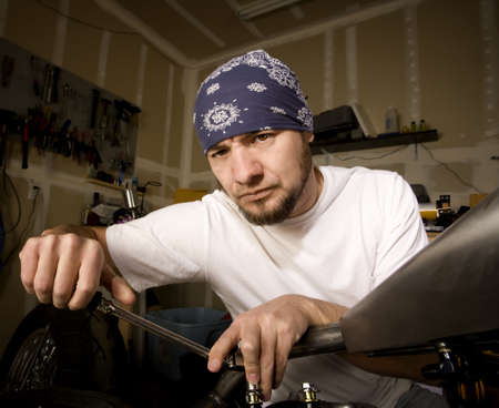 Hispanic mechanic working on a chopper style motorcycleの写真素材