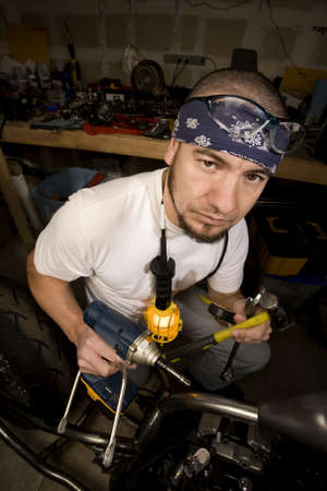 Hispanic mechanic working on a chopper style motorcycleの写真素材