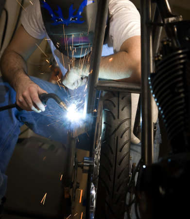 Welder working on the metal fork of a motorcycle