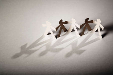 Line of cutout paper dolls throwing a shadowの写真素材